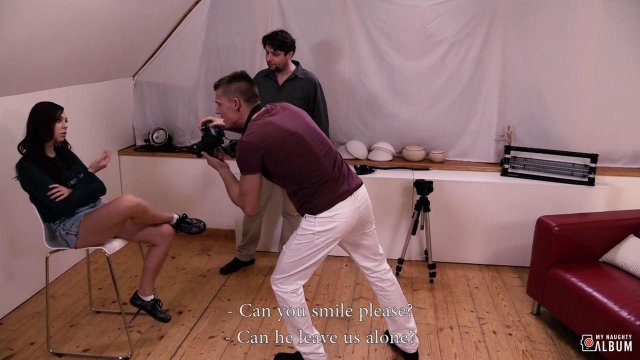 Модель в павильоне для съемок ласкает хуец фотографа на бордовом диване